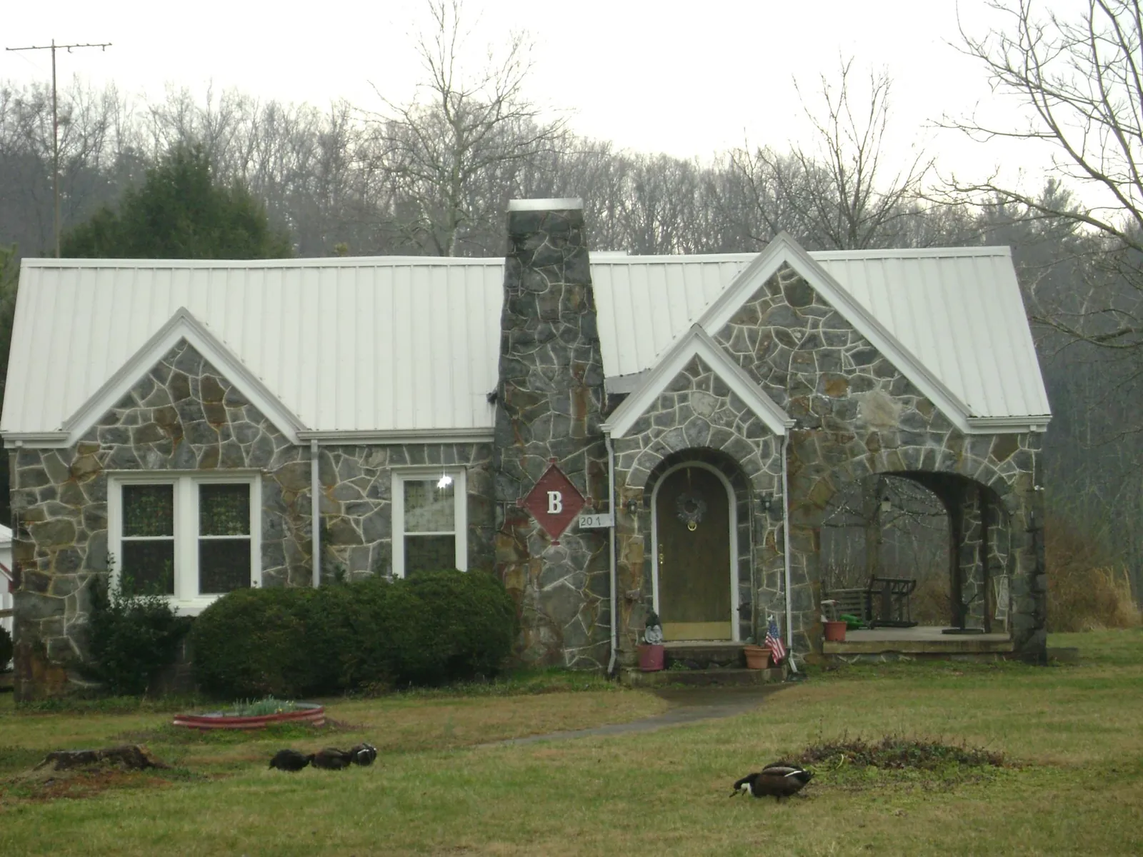 White metal roof on a stone cottage with steep gables in Syracuse